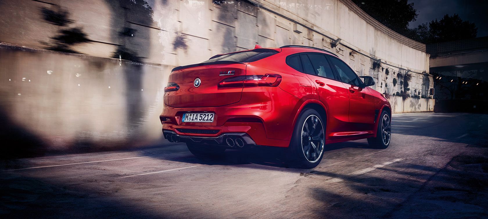 BMW X4 M Competition, tylny półprofil. BMW X4 M Competition, czerwień Toronto metalizowany, podczas jazdy, wygląd zewnętrzny, tylny półprofil.