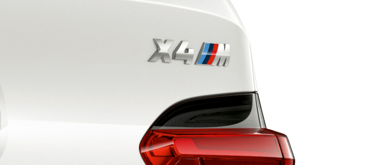 BMW X4 M, oznaczenie modelu. BMW X4 M, biel alpejska, wygląd zewnętrzny, zbliżenie tyłu z oznaczeniem modelu.