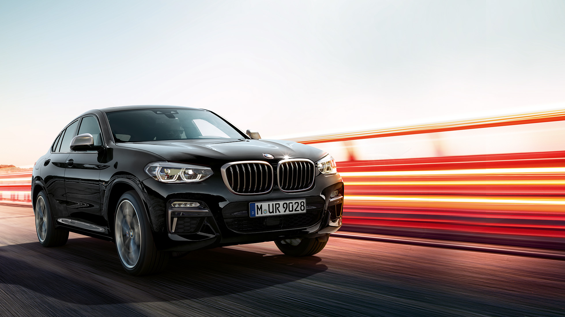 BMW X4 M40i, tylny półprofil. BMW X4 M40i, szafirowoczarny metalizowany, podczas jazdy, wygląd zewnętrzny, tylny półprofil z pasami świetlnymi.
