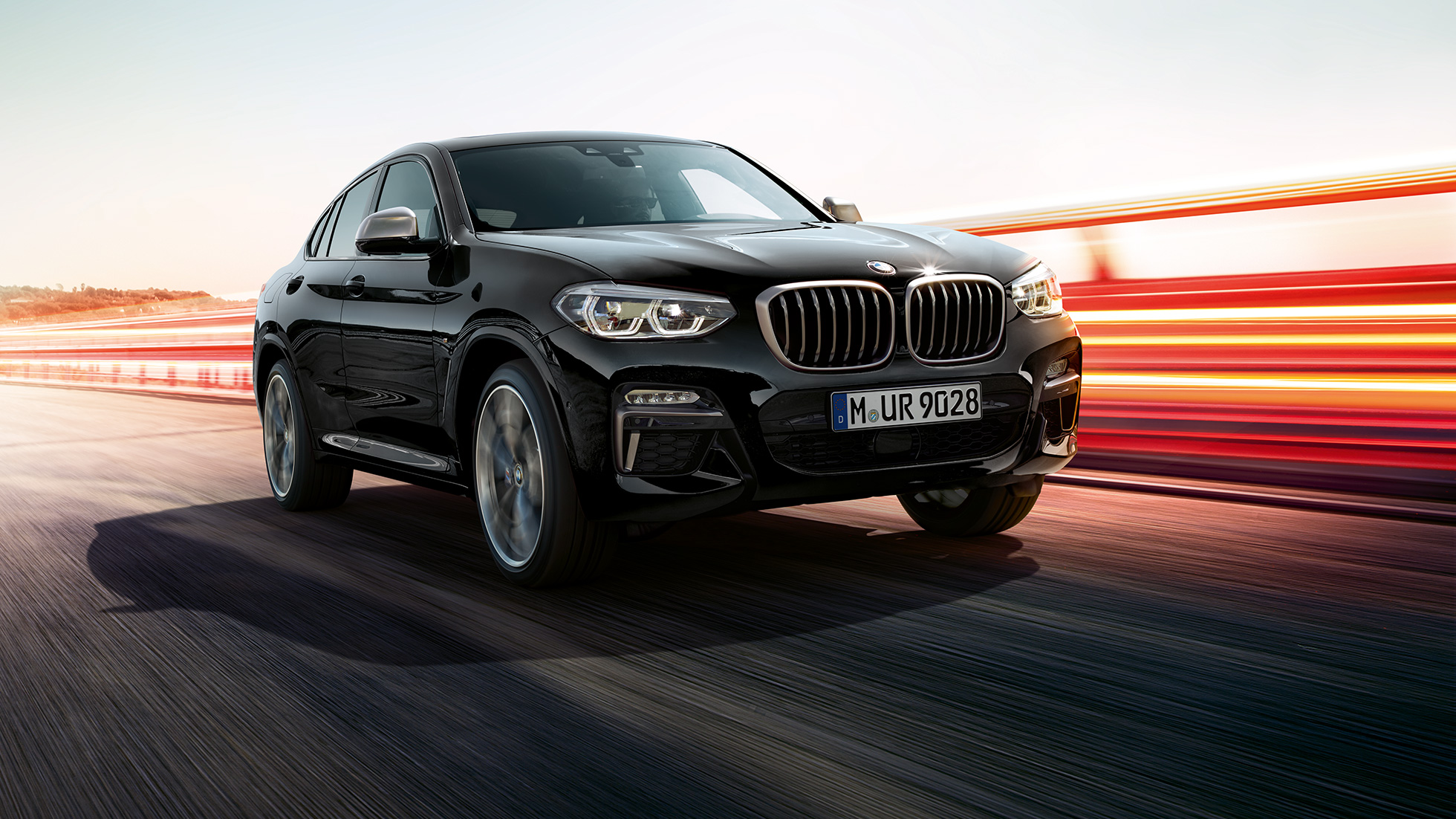 BMW X4 M40i oraz BMW X4 M40d, przedni półprofil. BMW X4 M40i oraz BMW X4 M40d, szafirowoczarny metalizowany, wygląd zewnętrzny, półprofil z lewej z pasami świetlnymi.