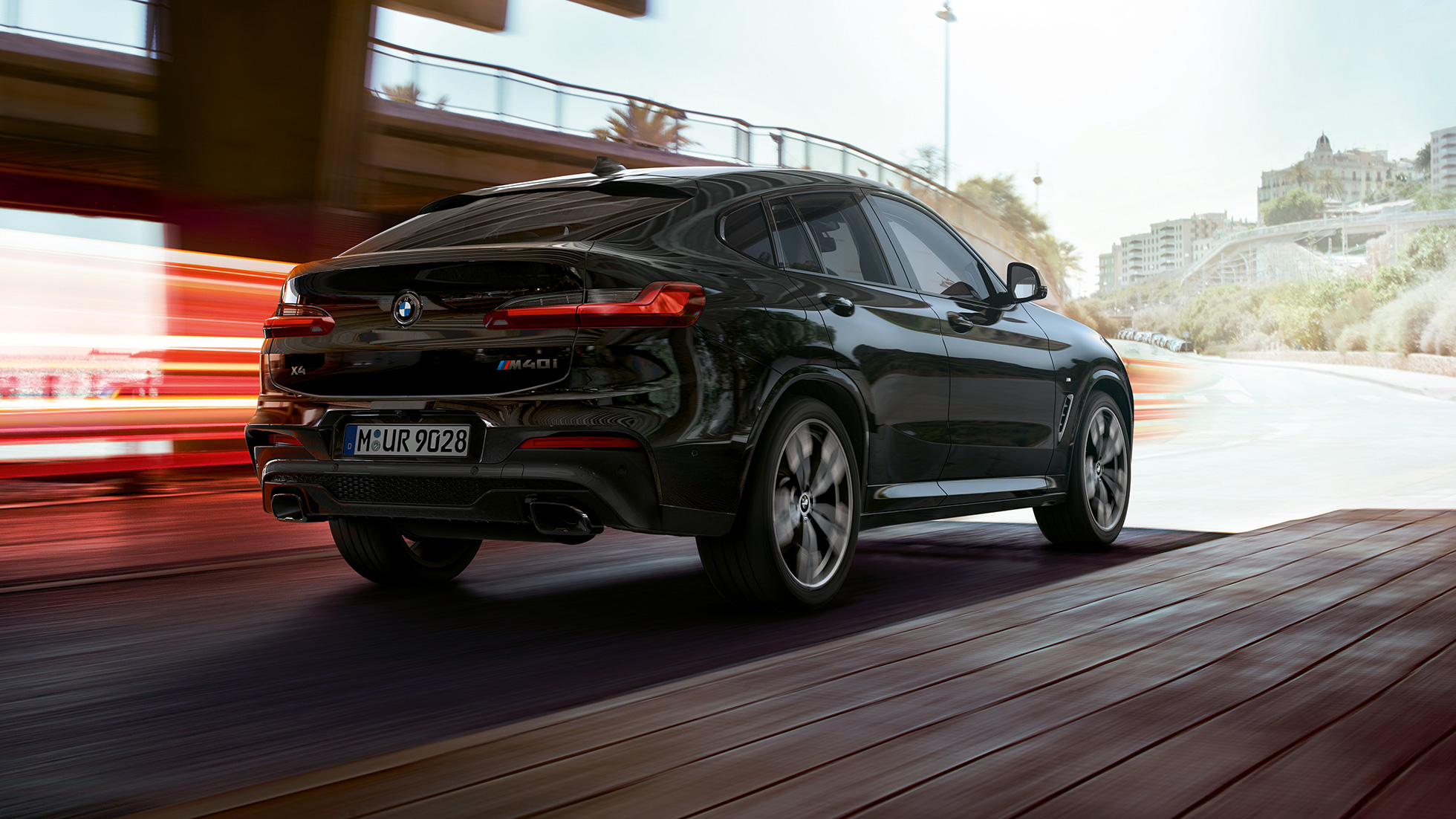 BMW X4 M40i, tylny półprofil. BMW X4 M40i, szafirowoczarny metalizowany, wygląd zewnętrzny, prawy tylny półprofil z pasami świetlnymi.