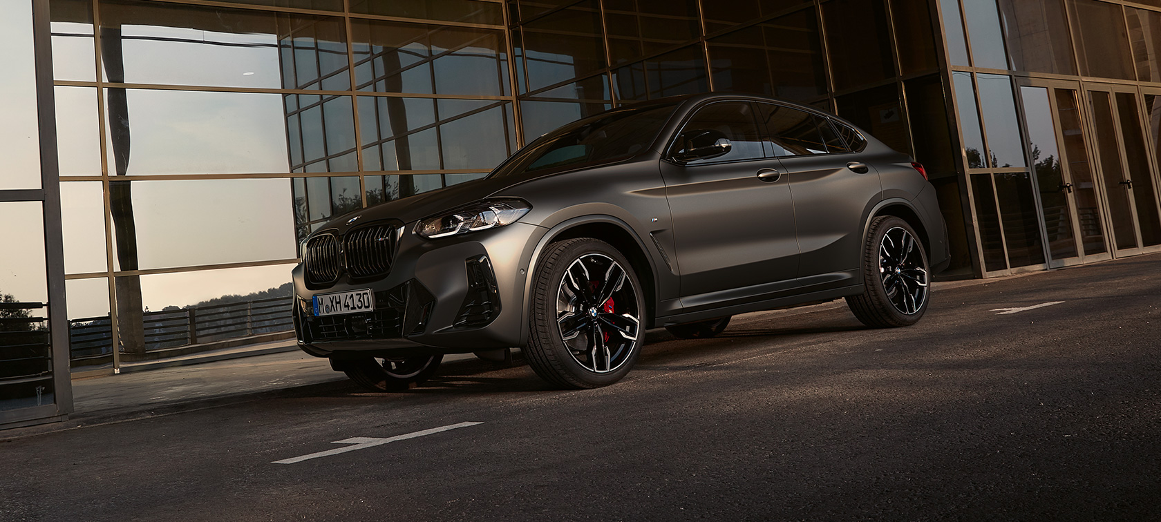 Przedni półprofil BMW X4 M40i G02 LCI modernizacja 2021 BMW X4 M40i G02 LCI modernizacja 2021 przedni półprofil przed fasadą szklaną
