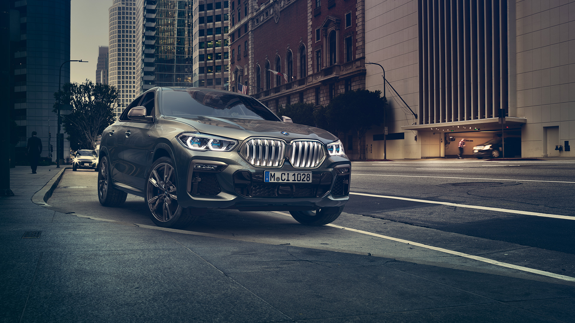 BMW X6 M50i na postoju BMW X6 M 50i z perspektywy przedniego półprofilu na tle miasta