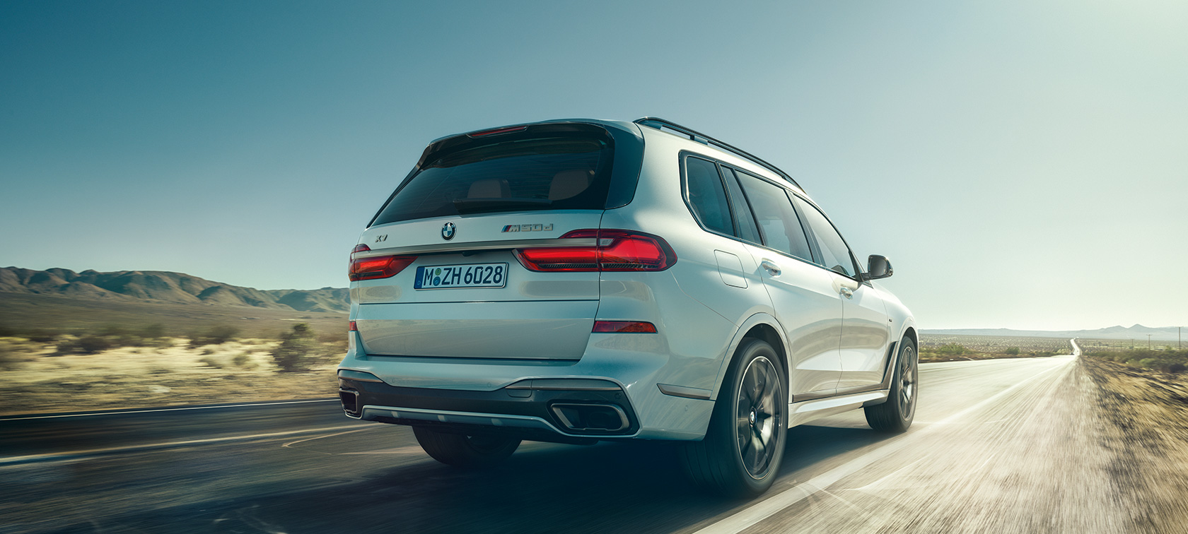BMW X7 M50d, widok z tyłu BMW X7 M50d w kolorze bieli mineralnej, widok z tyłu podczas jazdy na pustej drodze, G07, 2019