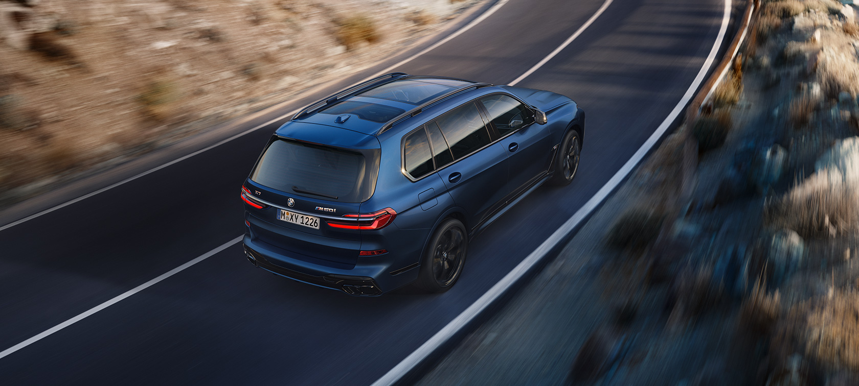BMW X7 M60i xDrive G07 LCI mroźny niebieski Marina Bay tylny półprofil widok z góry podczas jazdy BMW X7 M60i xDrive G07 LCI mroźny niebieski Marina Bay tylny półprofil widok z góry podczas jazdy na drodze