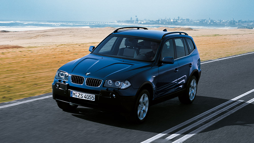 BMW X3 E83 pierwsza generacja przedni półprofil podczas jazdy na ulicy Modele BMW X BMW X3 E83 pierwsza generacja przedni półprofil podczas jazdy na ulicy