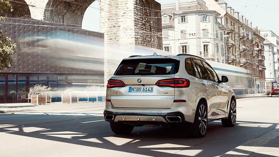BMW X5 G05 czwarta generacja tylny półprofil podczas postoju na tle budynku Modele BMW X BMW X5 G05 czwarta generacja tylny półprofil podczas postoju na tle budynku