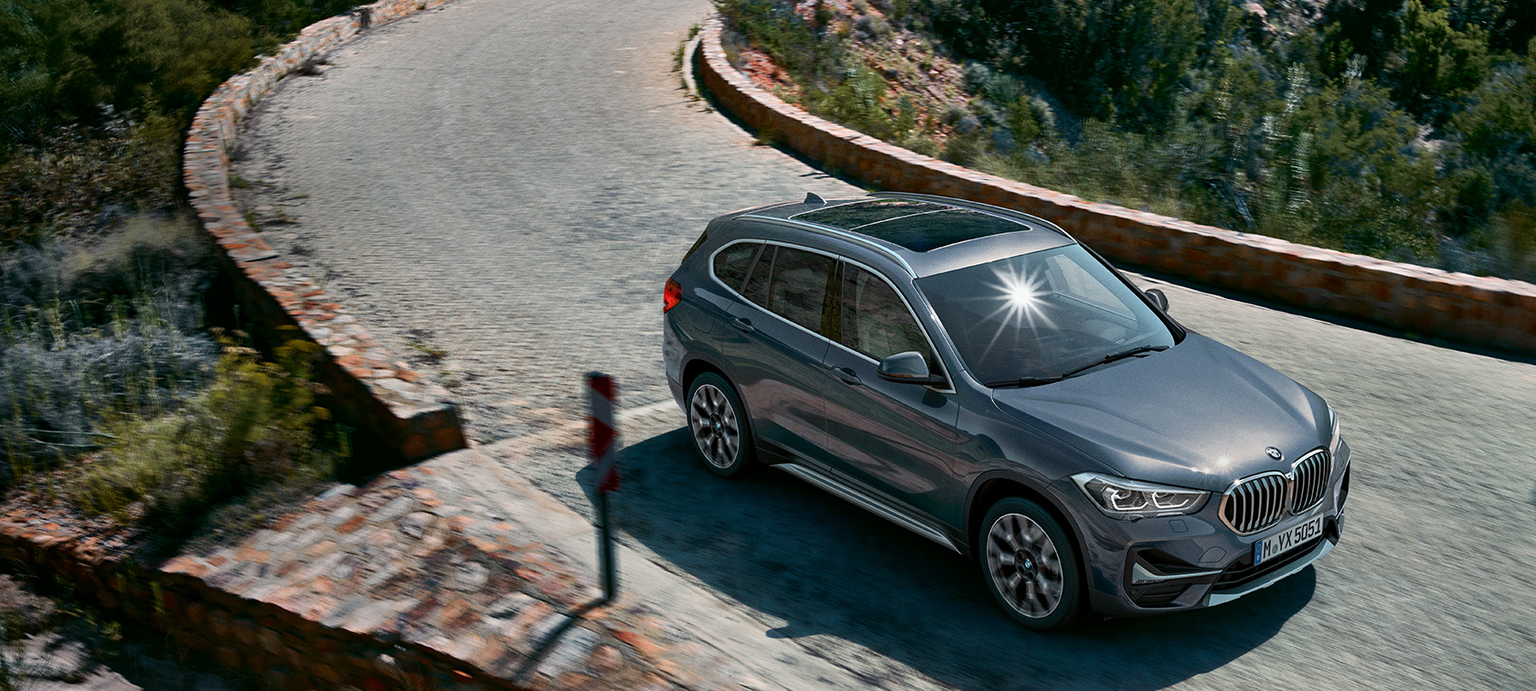 BMW X1, ujęcie z półprofilu od przodu. BMW X1, ujęcie z półprofilu od przodu, jadący na tle krajobrazu górskiego.