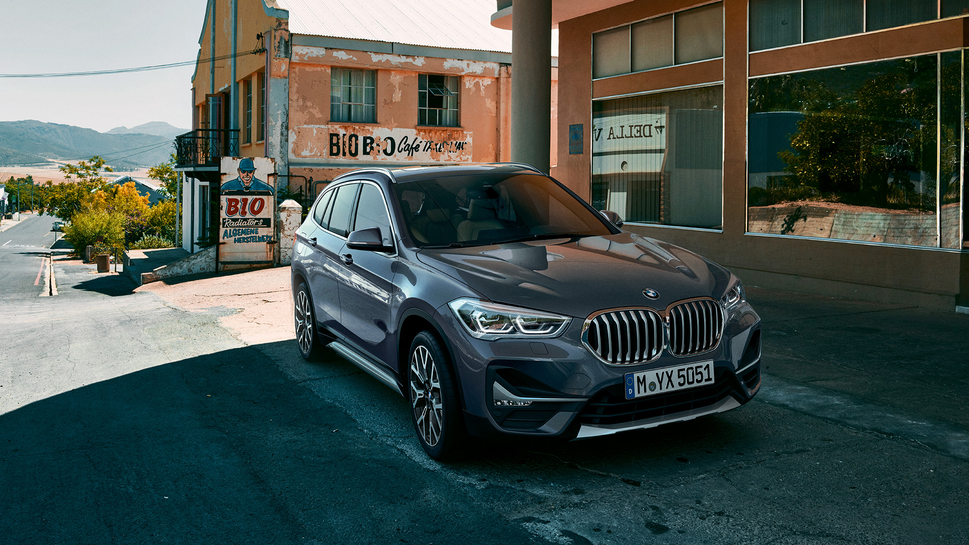 BMW X1, ujęcie z półprofilu od przodu. BMW X1, ujęcie z półprofilu od przodu, zaparkowany na tle scenerii miejskiej.