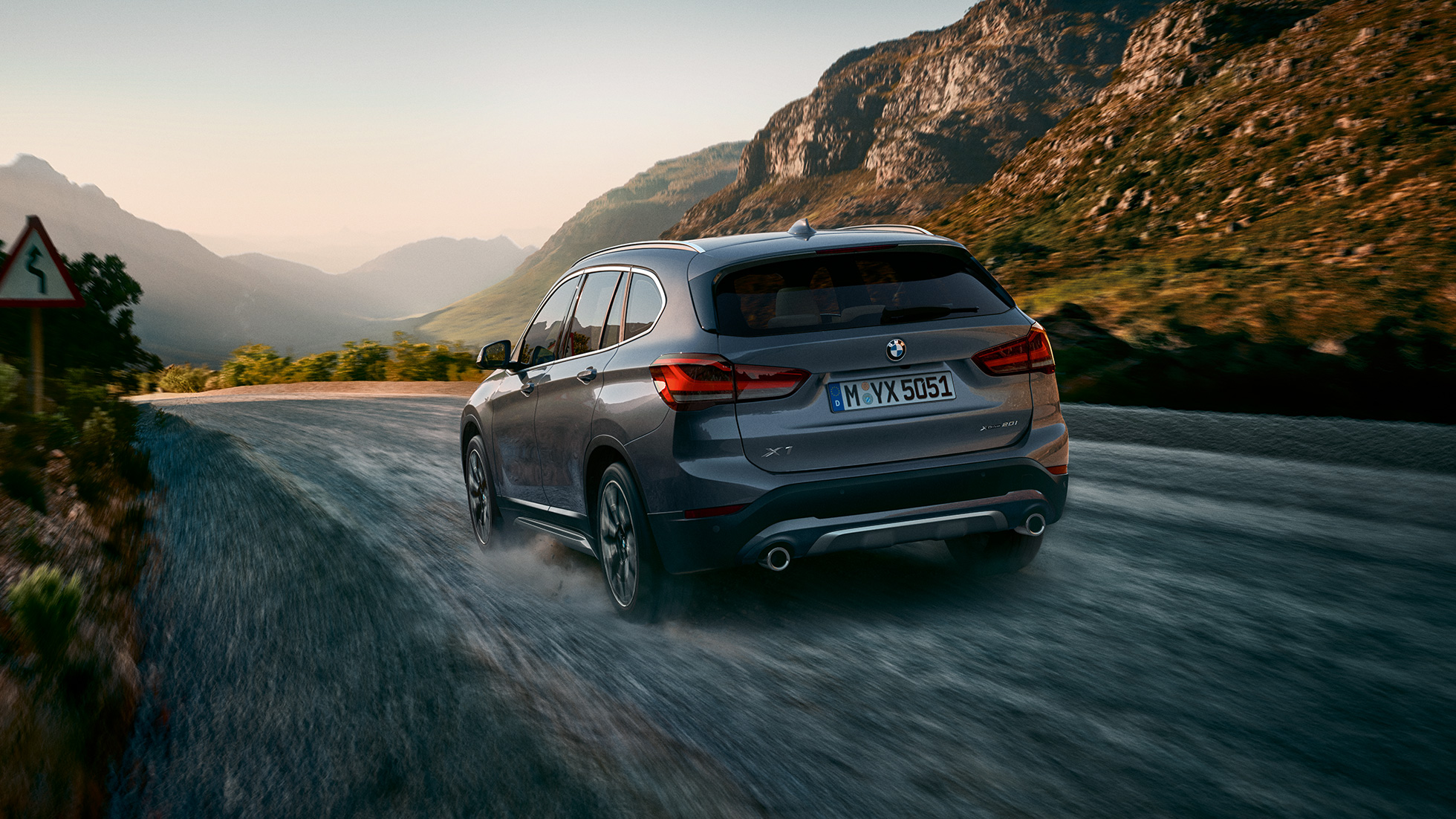 BMW X1, ujęcie z półprofilu od tyłu. BMW X1, ujęcie z półprofilu od tyłu, jadący na tle krajobrazu górskiego.
