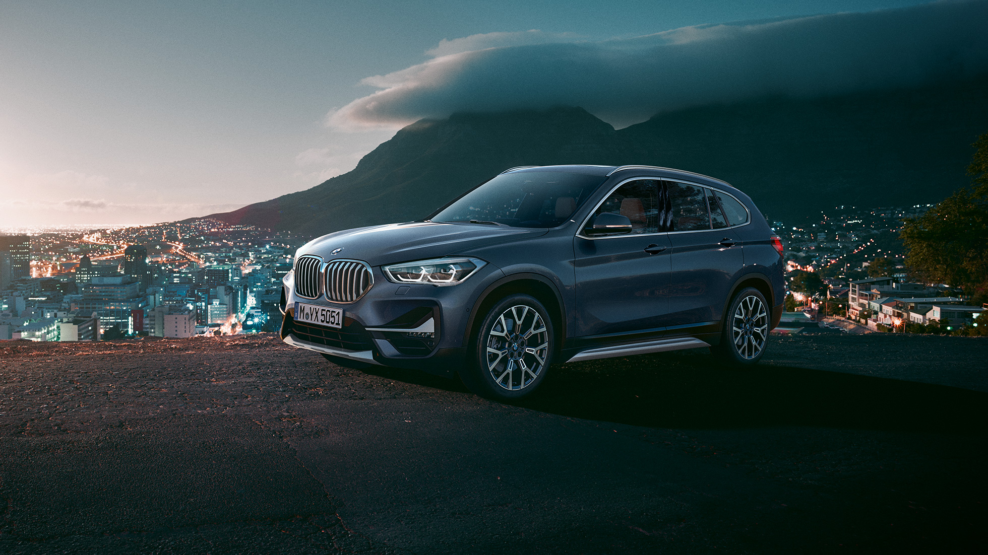BMW X1, ujęcie z półprofilu od boku. BMW X1, ujęcie z półprofilu od boku, jadący na tle scenerii miejskiej.