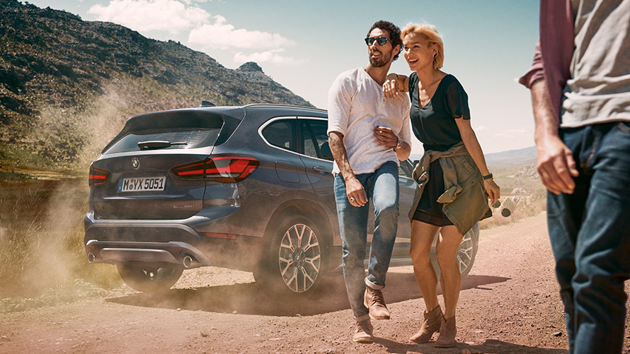 BMW X1 F48 LCI Storm Bay tylny półprofil BMW X1 F48 LCI Storm Bay tylny półprofil podczas postoju w naturze z osobą przed nim
