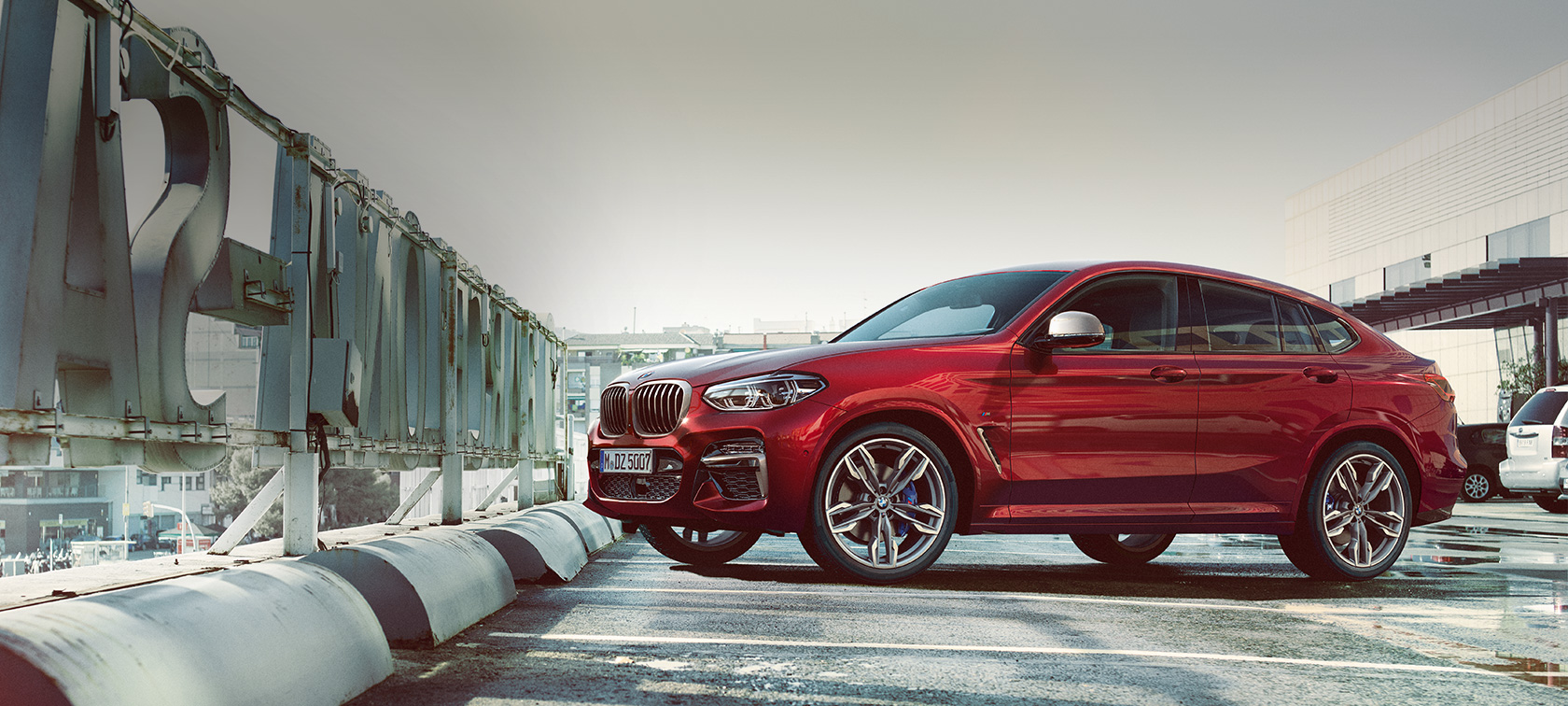 Widok z boku parkującego BMW X4 BMW X4 M40i G02 2018 czerwień Flamenco z brylantowym połyskiem, widok z boku