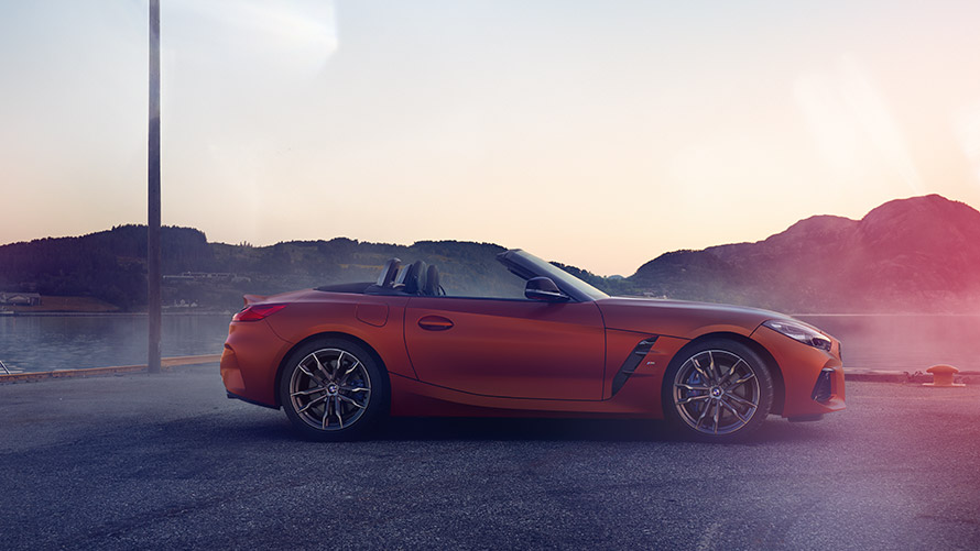 Boczny widok na pomarańczowe BMW Z4 First Edition Boczny widok na pomarańczowe BMW Z4 First Edition na tle gór