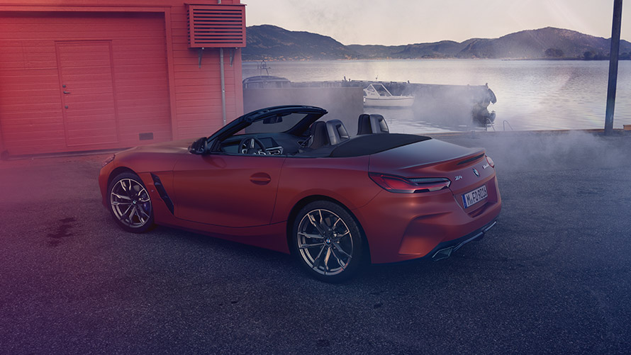 Tylny widok na pomarańczowe BMW Z4 First Edition Boczny widok na pomarańczowe BMW Z4 First Edition przed czerwonym domem na wybrzeżu
