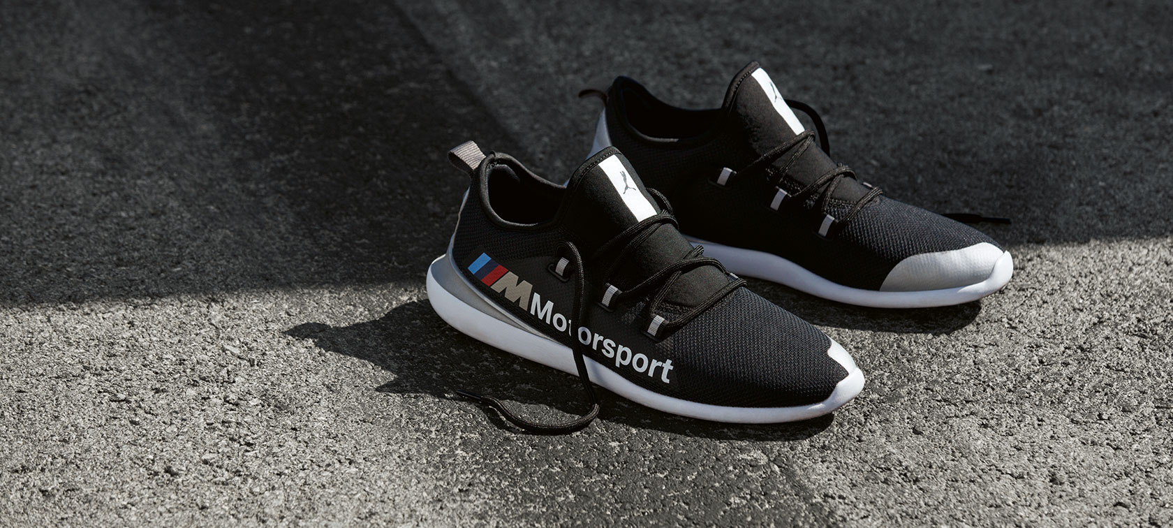 Buty BMW M Motorsport PUMA EVO CAT. Na zdjęciu widać parę butów BMW M Motorsport PUMA EVO CAT z kolekcji BMW M Motorsport, ustawionych na asfaltowej nawierzchni.