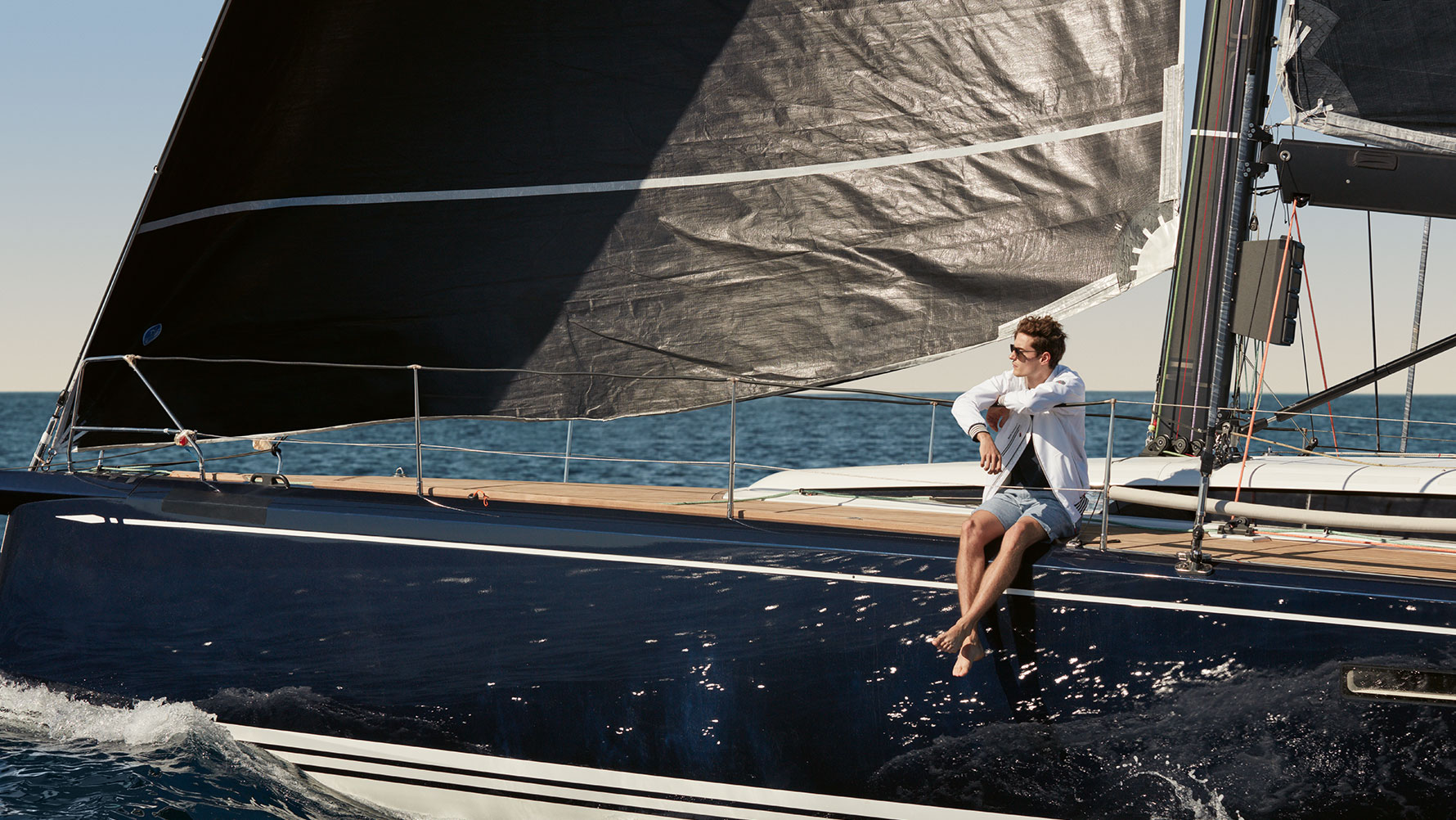 Pokazany jest siedzący w jachcie mężczyzna ubrany w męską kurtkę BMW Yachtsport z kolekcji BMW Yachtsport. Pokazany jest siedzący w jachcie mężczyzna ubrany w męską kurtkę BMW Yachtsport z kolekcji BMW Yachtsport.