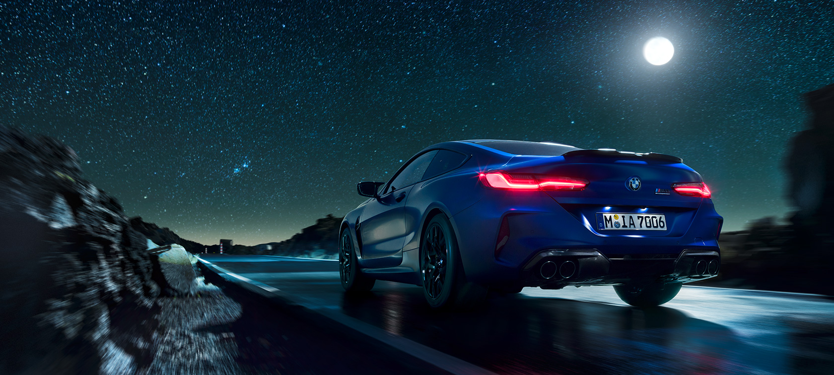 BMW M8 Competition Coupé, widok z tyłu BMW M8 Competition Coupé, widok z tyłu, jadące nocą na tle pełni.