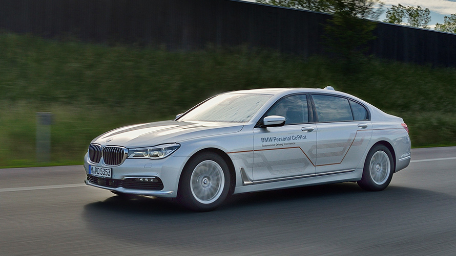 Szare BMW serii 7 Limuzyna Szary BMW Serii 5 Sedan oznaczony BMW Personal CoPilot jedzie z lewej strony na autostradzie.