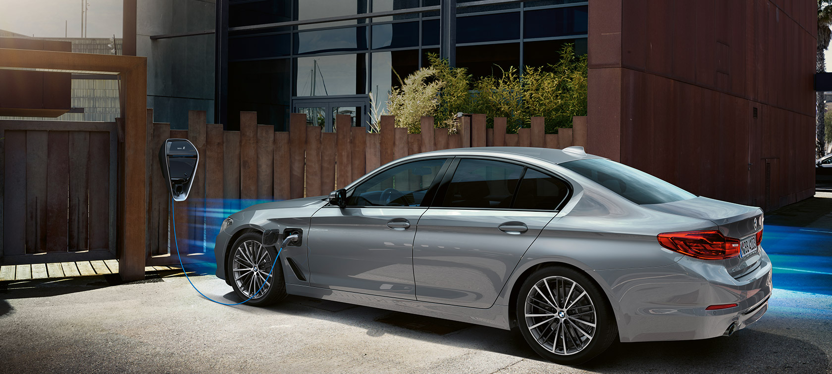BMW 530e przy stacji ładowania. BMW 530e półprofil przy stacji ładowania.