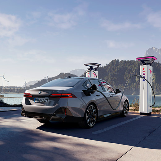 BMW i5 eDrive40 G60 przy stacji ładowania na tle jeziora