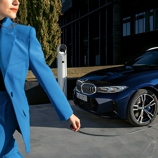 BMW podczas ładowania idąca kobieta na pierwszym planie