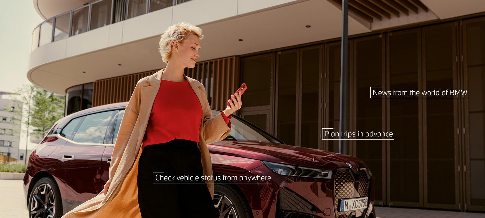 Kobieta przed białym BMW iX korzysta z aplikacji My BMW na smartfonie Kobieta przed białym BMW iX korzysta z aplikacji My BMW na smartfonie