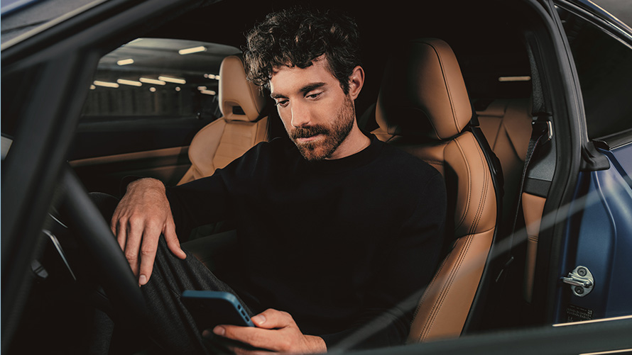 Mężczyzna siedzi w BMW Mężczyzna siedzi w BMW patrzy na swój smartfon