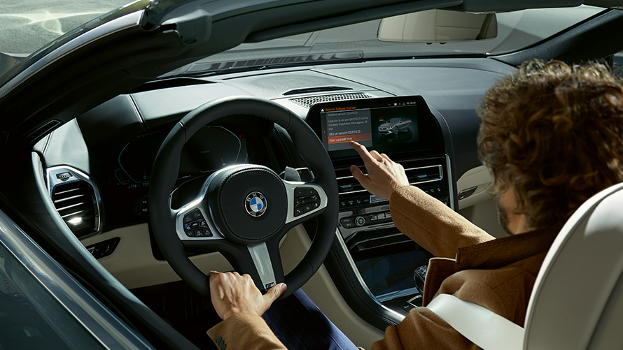Aktualizacja Zdalnego Oprogramowania Zdalna aktualizacja oprogramowania mężczyzna siedzący w BMW korzystający z wyświetlacza pokładowego.