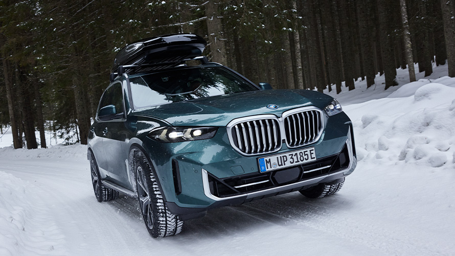 Kompletne koła zimowe BMW w BMW X5 (G05 LCI) na zaśnieżonej drodze w lesie Kompletne koła zimowe BMW w BMW X5 (G05 LCI) na zaśnieżonej drodze w lesie