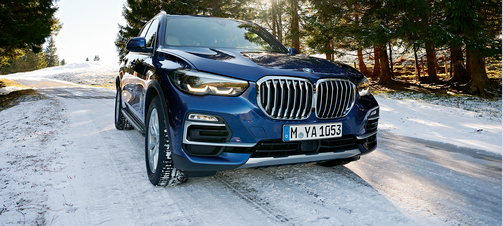 Akcesoria jesienne i zimowe BMW Niebieskie BMW X3 na zaśnieżonej ulicy, przedni półprofil