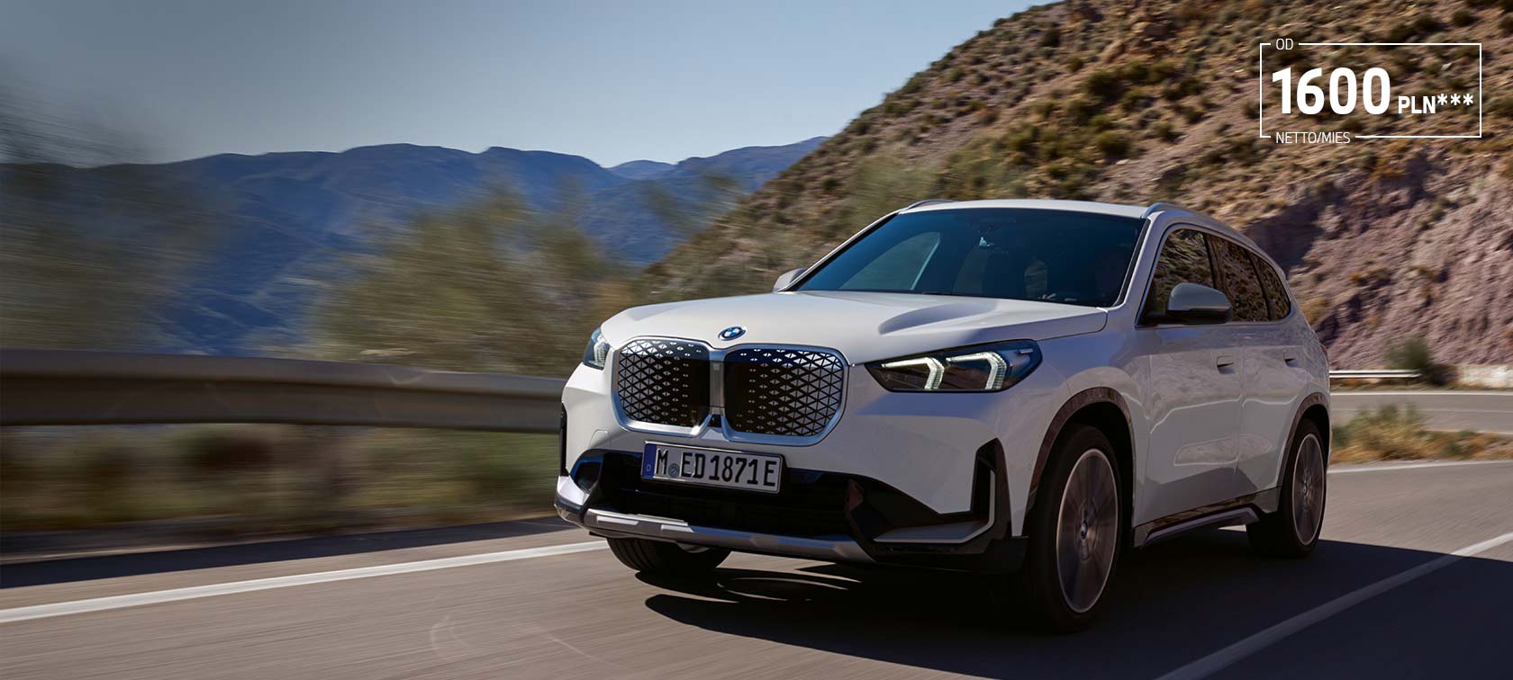 BMW iX1 U11 BEV 2022 biel mineralna metalizowany przedni półprofil podczas jazdy górską serpentyną