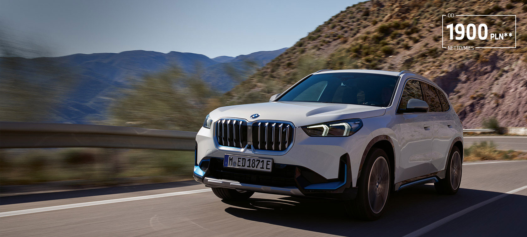BMW iX1 U11 BEV 2022 biel mineralna metalizowany przedni półprofil podczas jazdy górską serpentyną