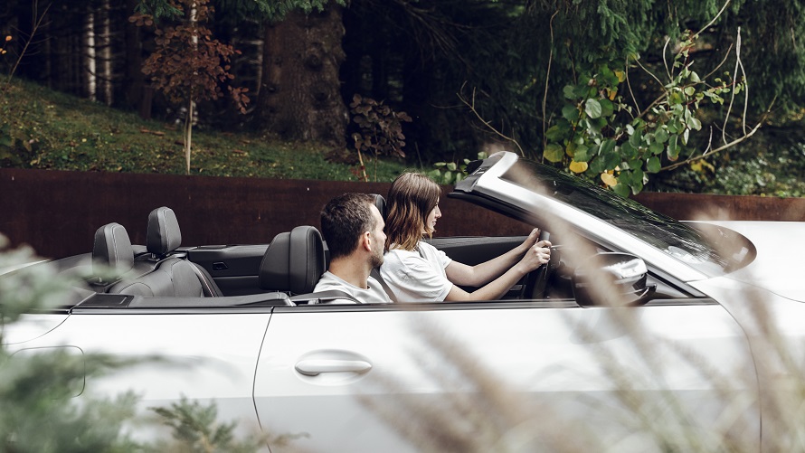 Kobieta prowadząca BMW B440i Cabrio z mężczyzną siedzącym na miejscu pasażera. Kobieta prowadząca BMW B440i Cabrio z mężczyzną siedzącym na miejscu pasażera.