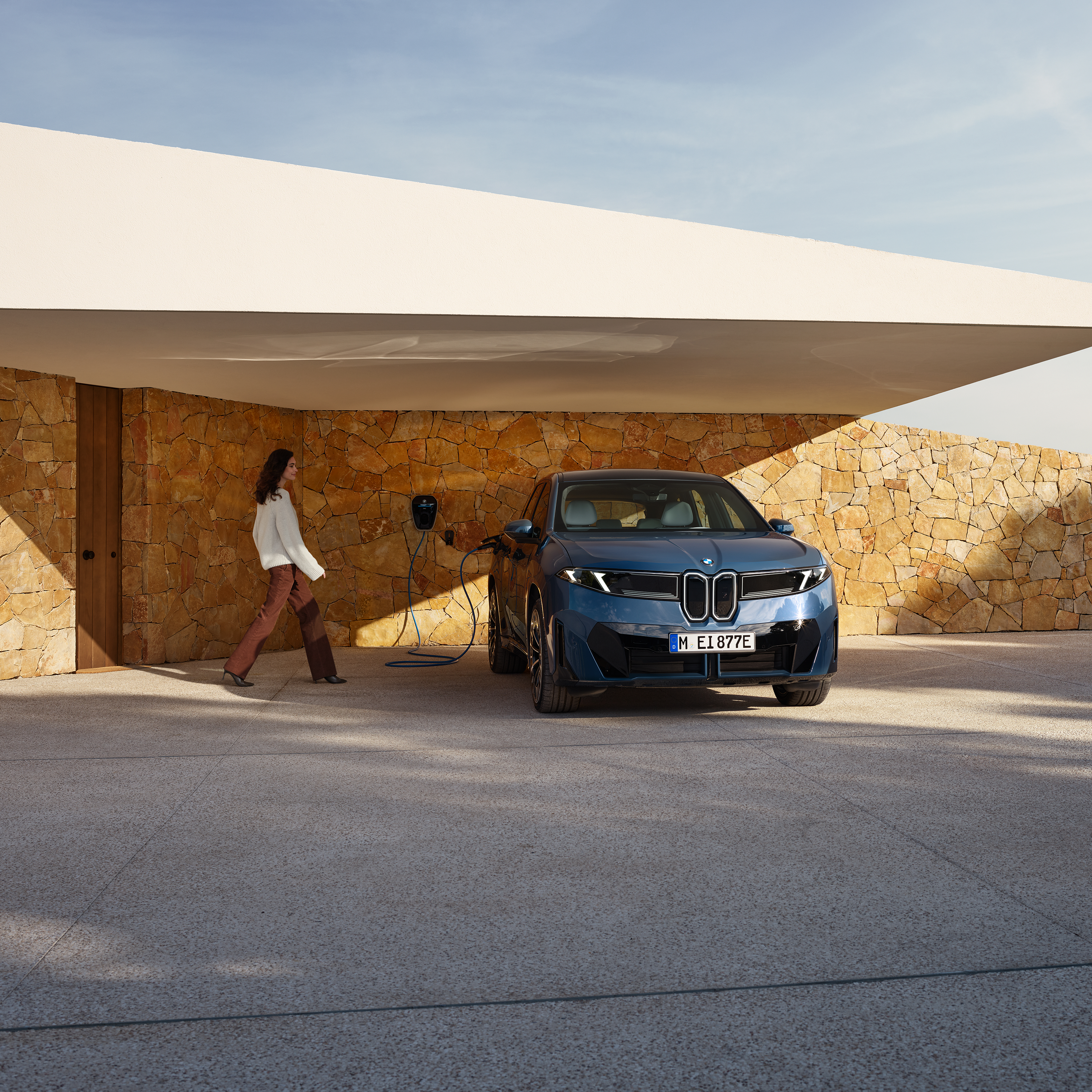 Kobieta zbliża się do BMW iX3 podłączonego do stacji Wallbox