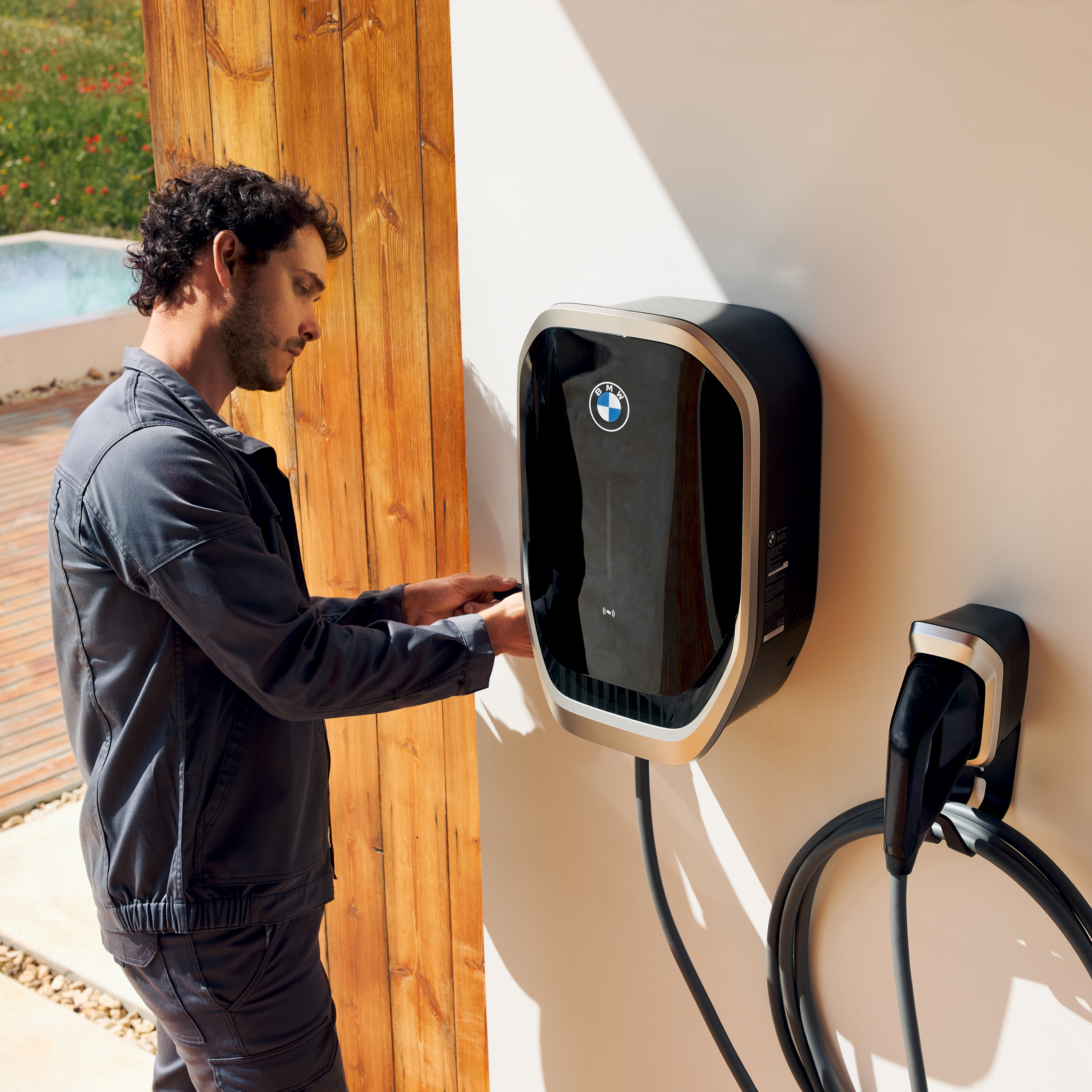 Osoba podłącza kabel ładowania do stacji BMW Wallbox